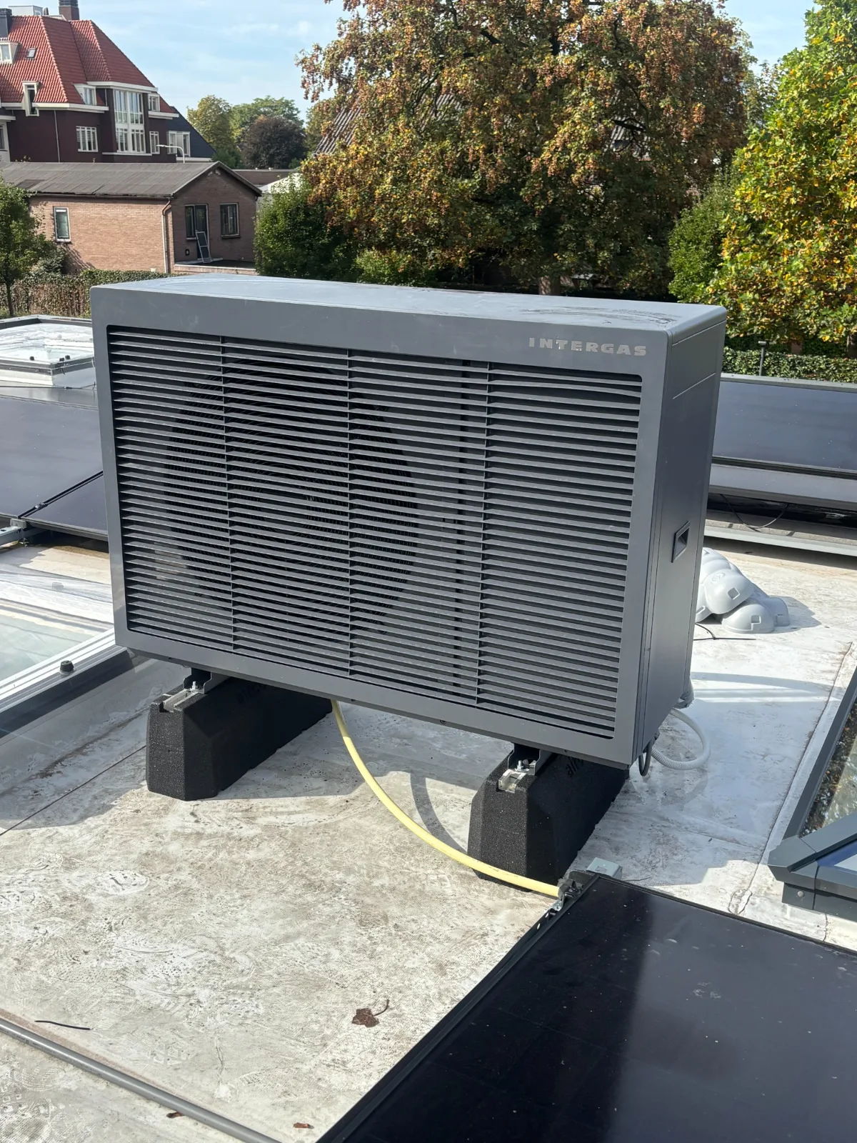 Buitendeel van een warmtepomp op een plat dak
