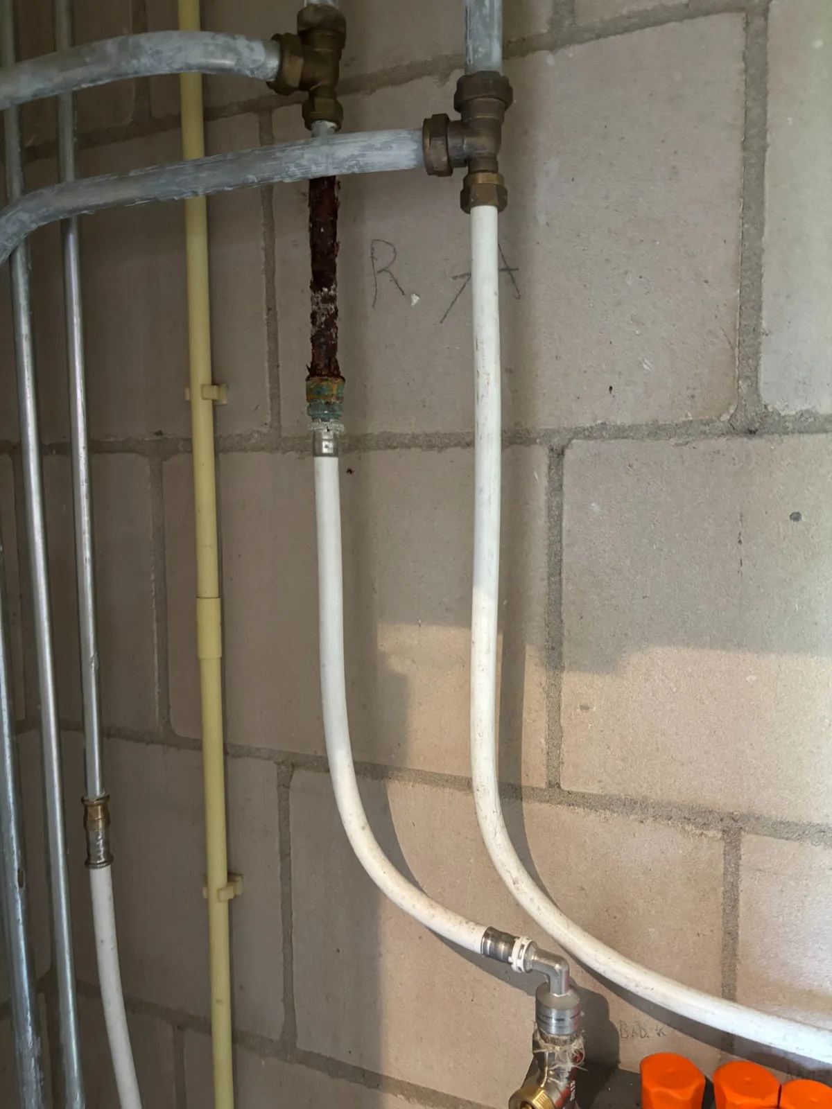 Oude leidingen met roest tegen een gemetselde muur