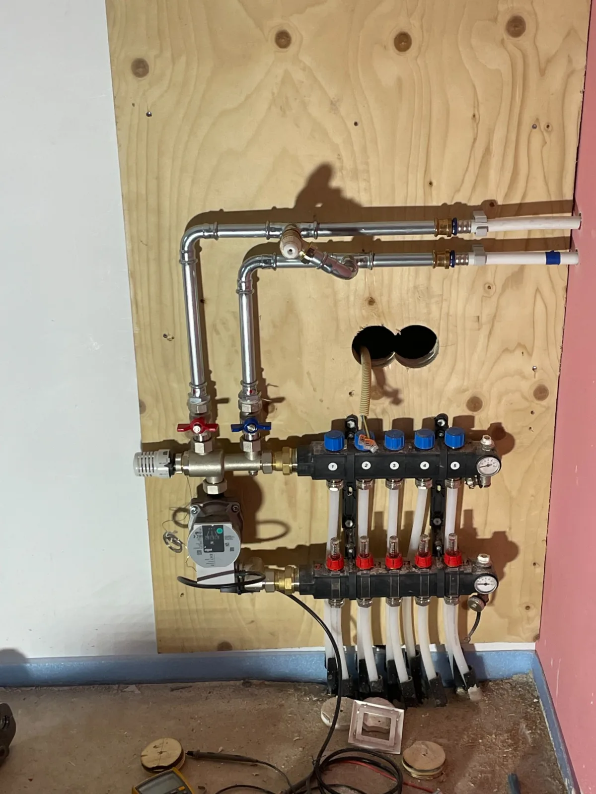 Nieuwe verdeler voor vloerverwarming op een houten achterplaat