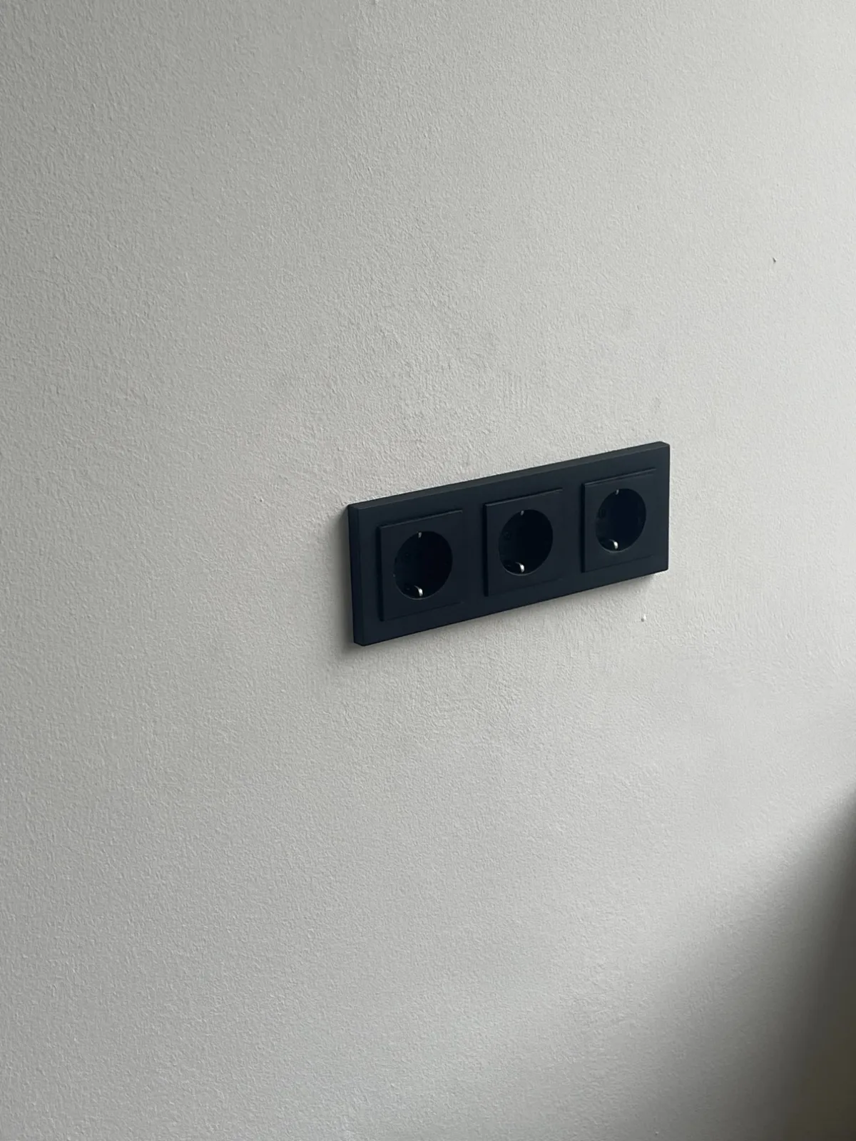 Zwart drievoudig stopcontact op een witte wand